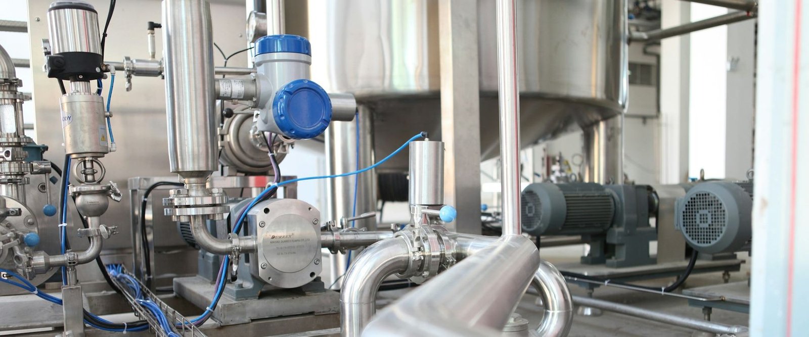 Installation industrielle : cuve et tuyauteries inox, vannes et moteurs